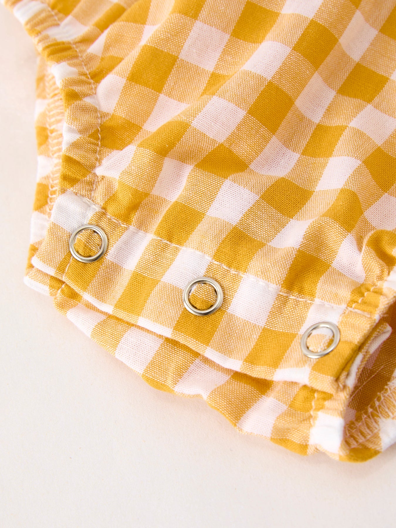 Baby girls yellow gingham bubble romper with pumpkin and turkey smocking, ruffle sleeves, Peter Pan collar, and bow accents.