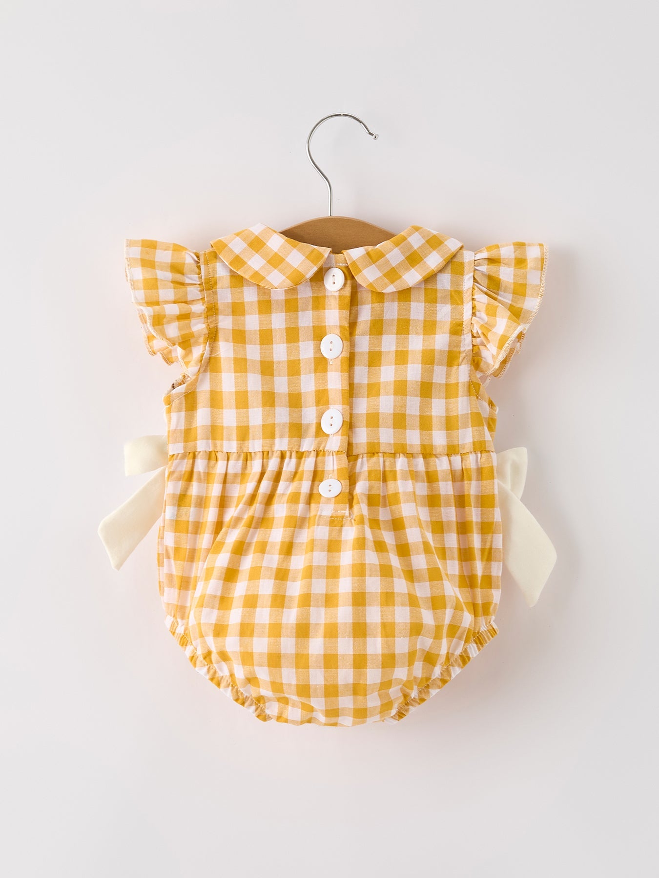Baby girls yellow gingham bubble romper with pumpkin and turkey smocking, ruffle sleeves, Peter Pan collar, and bow accents.