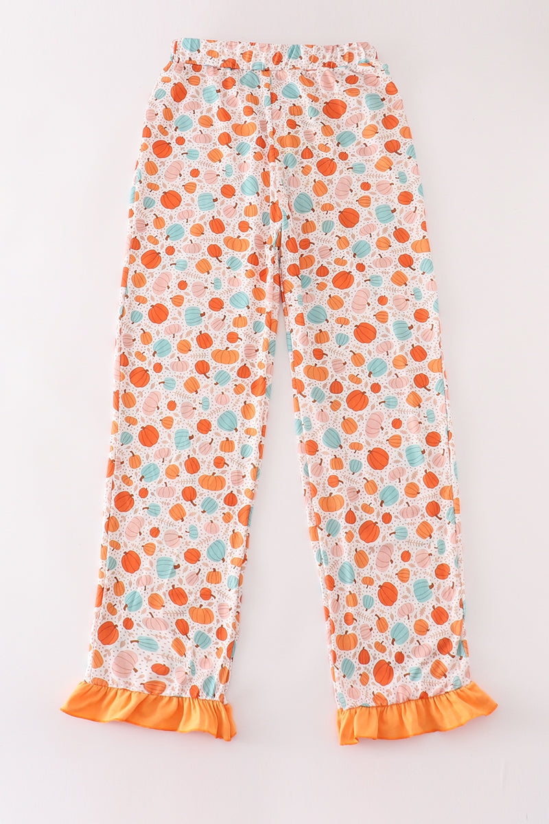 Floral-patterned pants with orange ruffle trim on a white background
