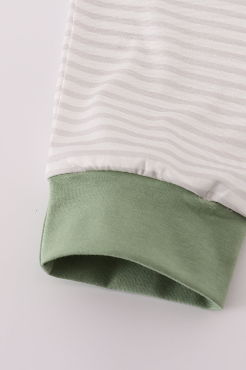 Close-up of a striped fabric with a green hem on a light gray background