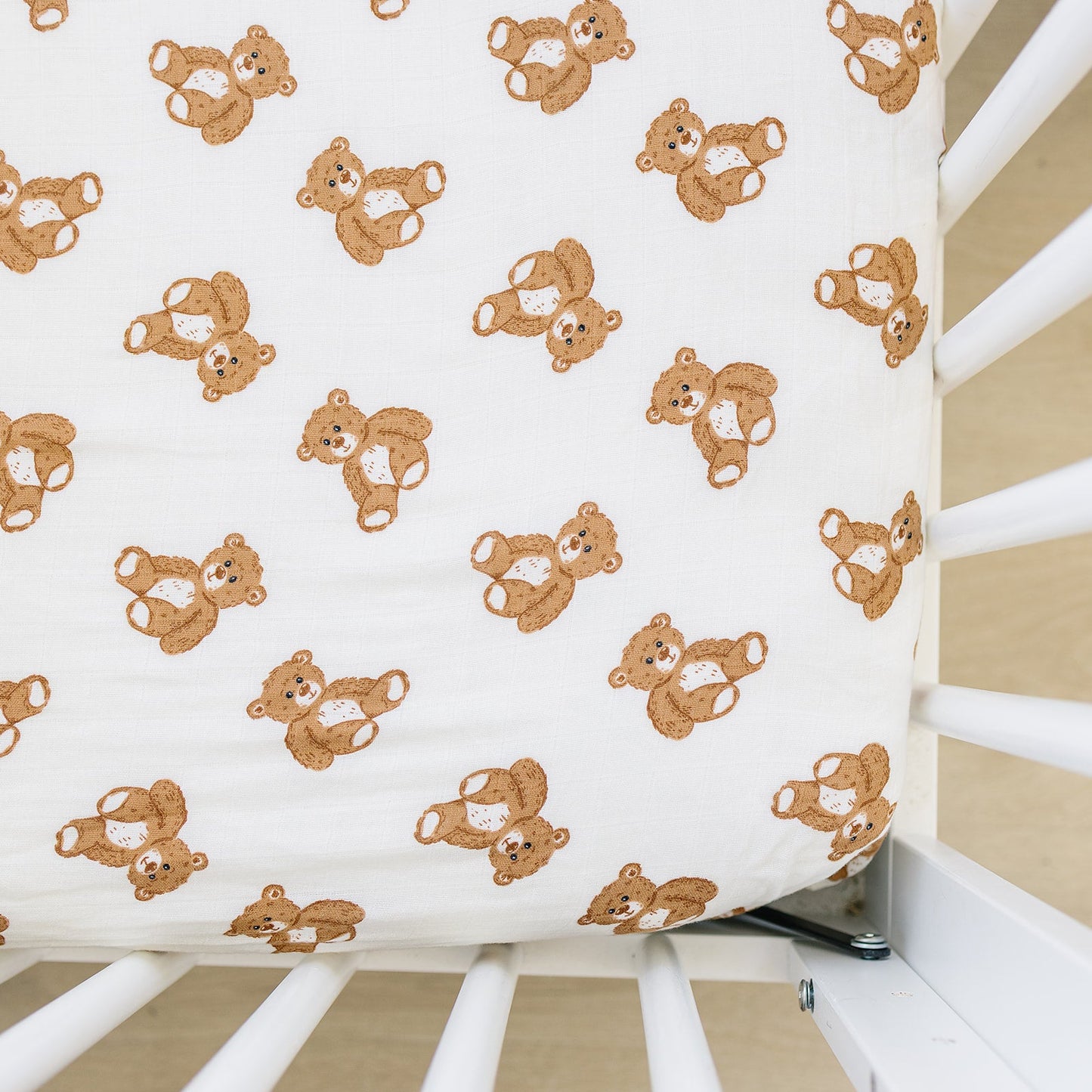 Fitted crib sheet with teddy bear pattern on a crib