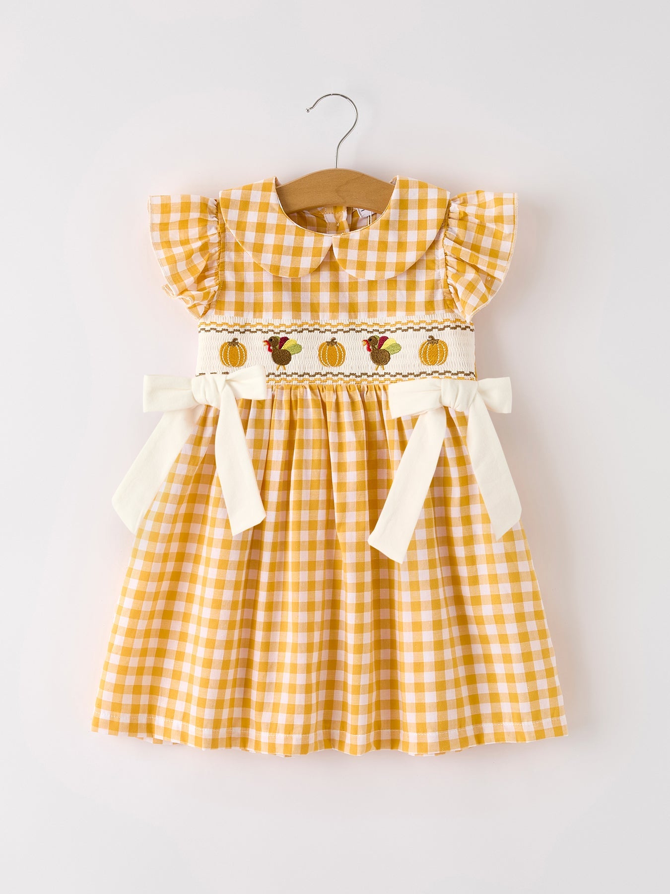 Girls yellow gingham Thanksgiving smocked dress with embroidered pumpkins, turkey, ruffle sleeves, and bow accents.