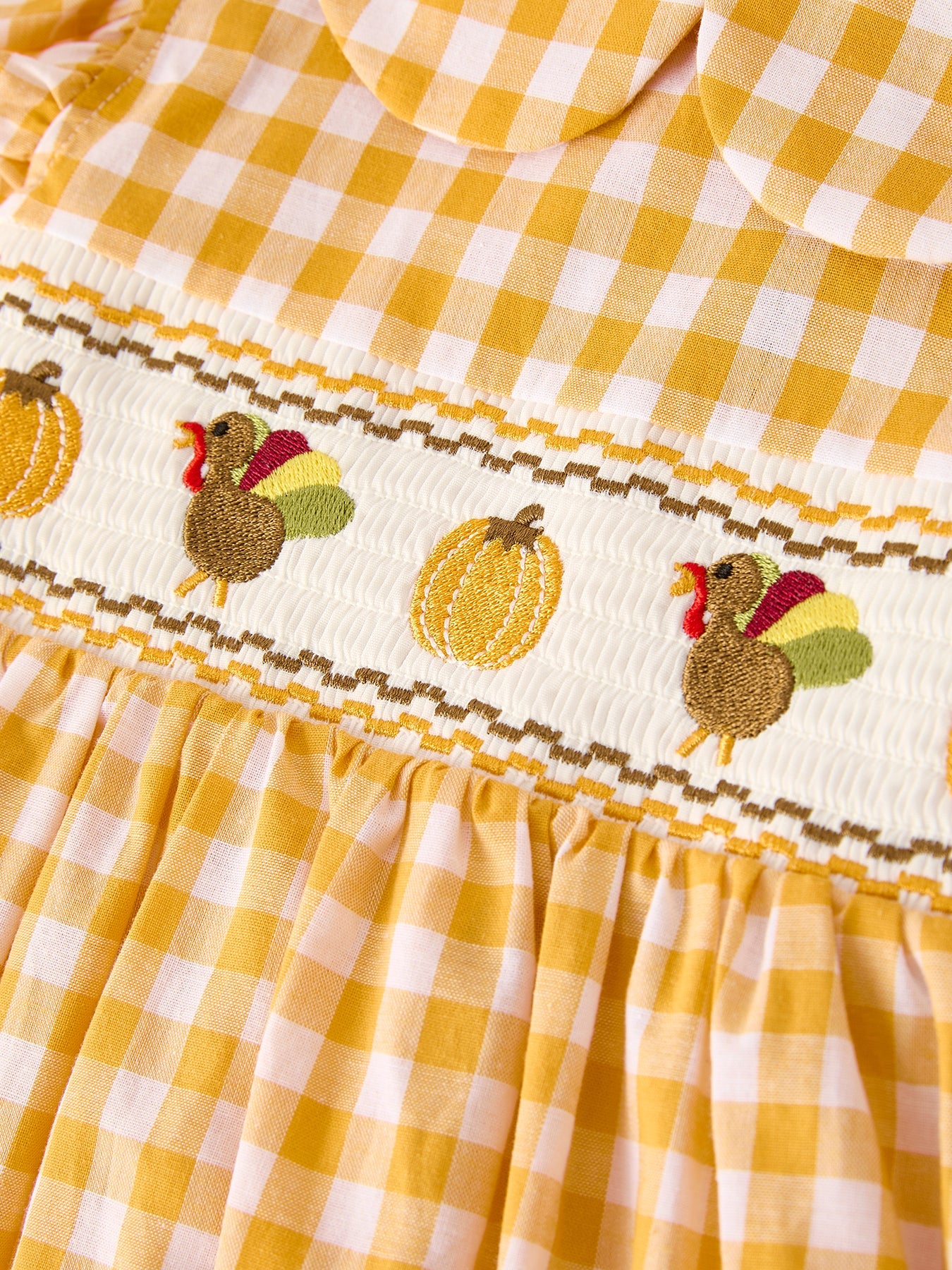 Girls yellow gingham Thanksgiving smocked dress with embroidered pumpkins, turkey, ruffle sleeves, and bow accents.