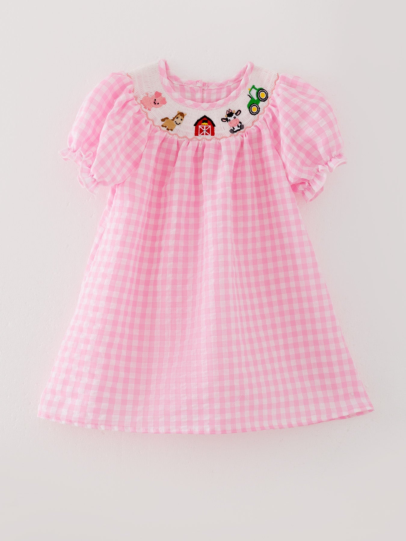 Pink checkered dress with embroidered designs on a light gray background