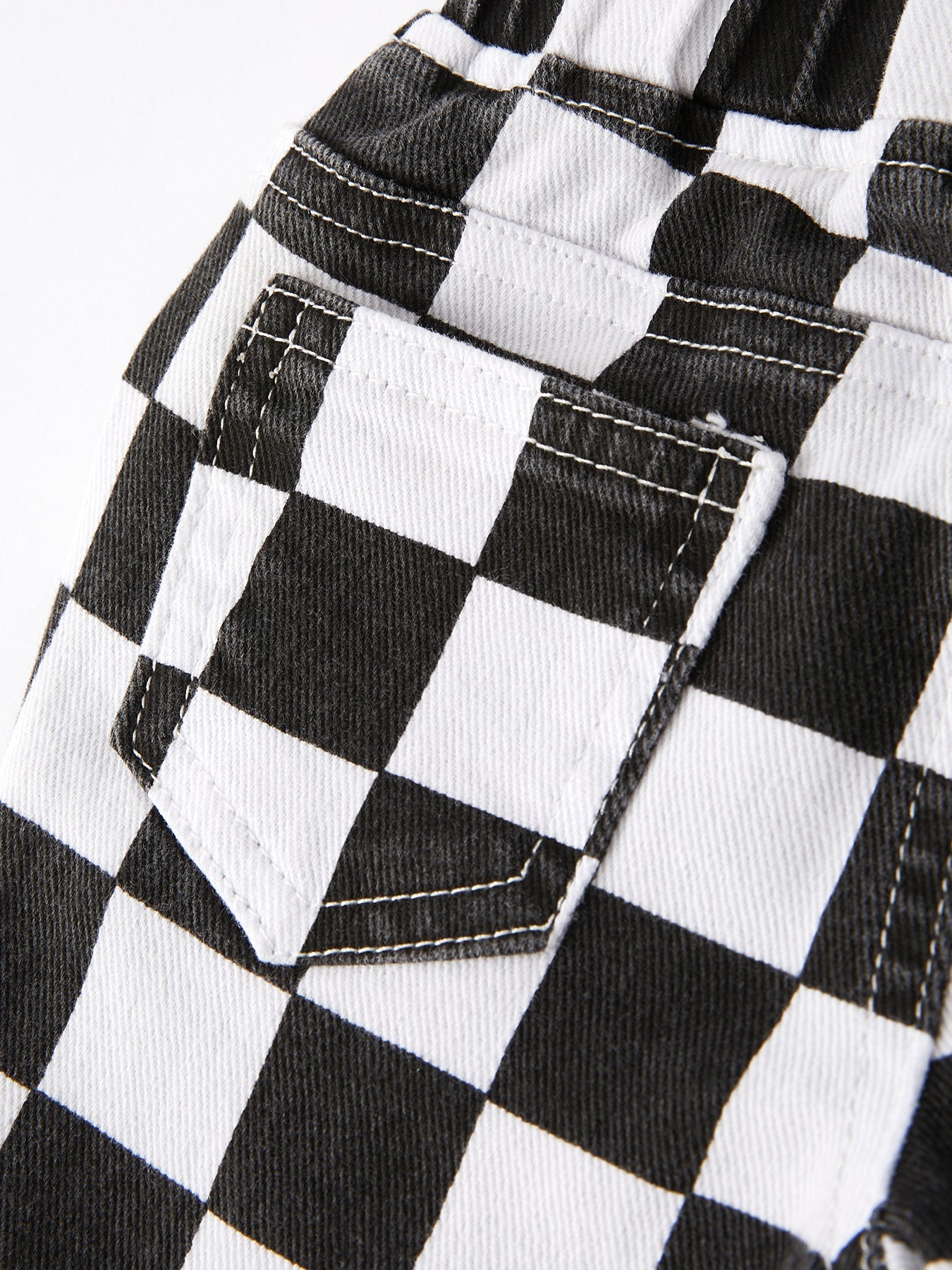 Close-up of a black and white checkered flare jeans for toddler and tween girls on fabric.