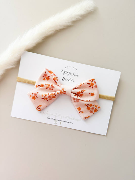 Blush floral baby bow headband on soft nude nylon band for infant girl