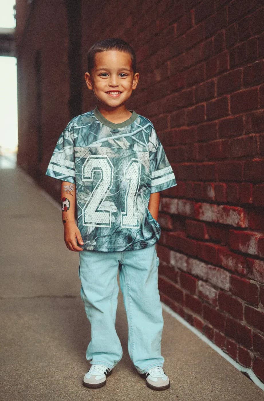Little boy in camo game day shirt with football