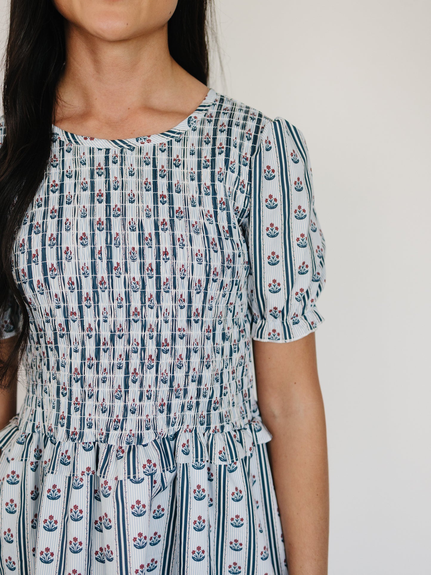Woman wearing a patterned dress with a plain background