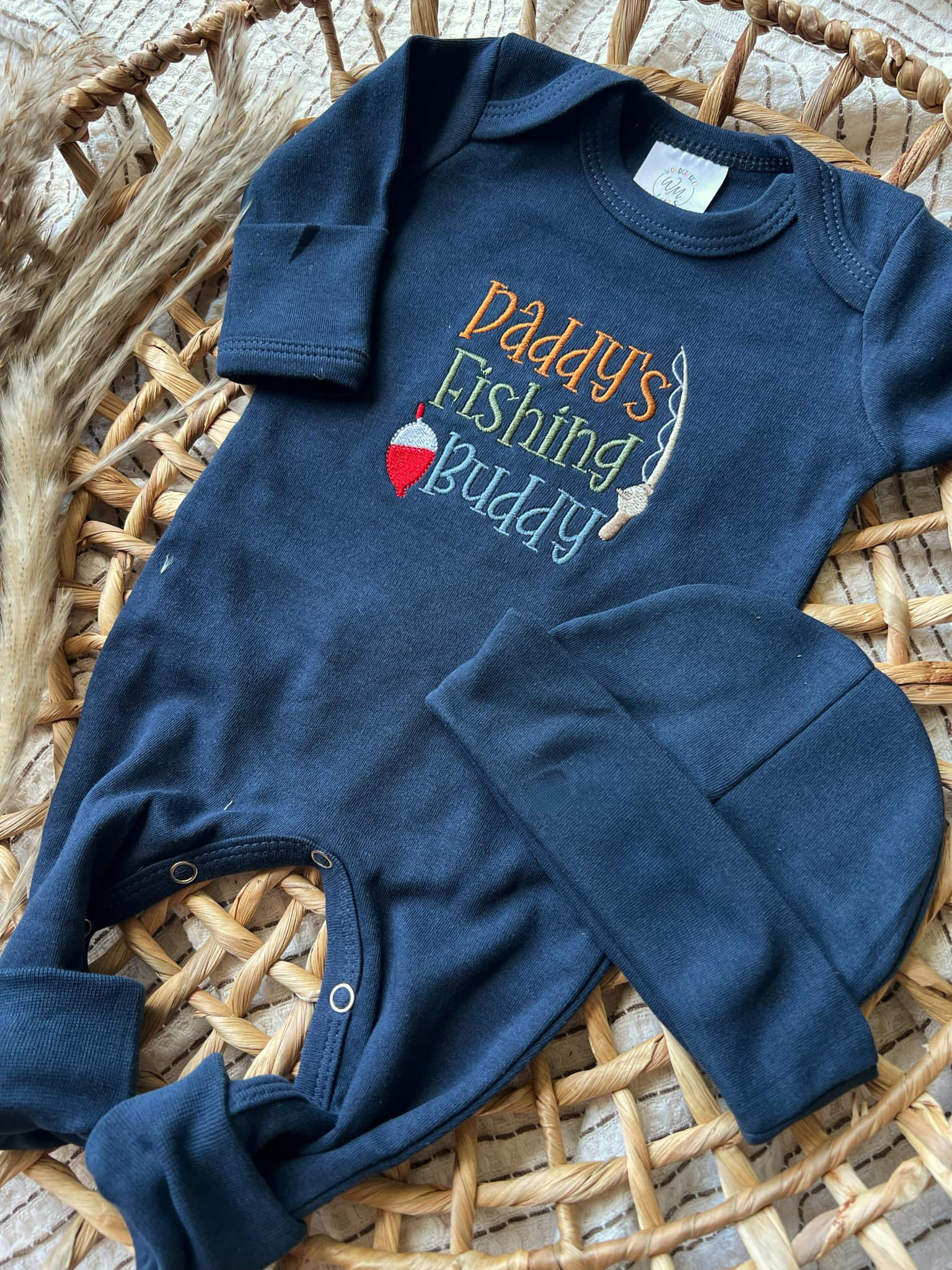 Navy blue baby romper with 'Daddy's Fishing Buddy' text on a woven surface