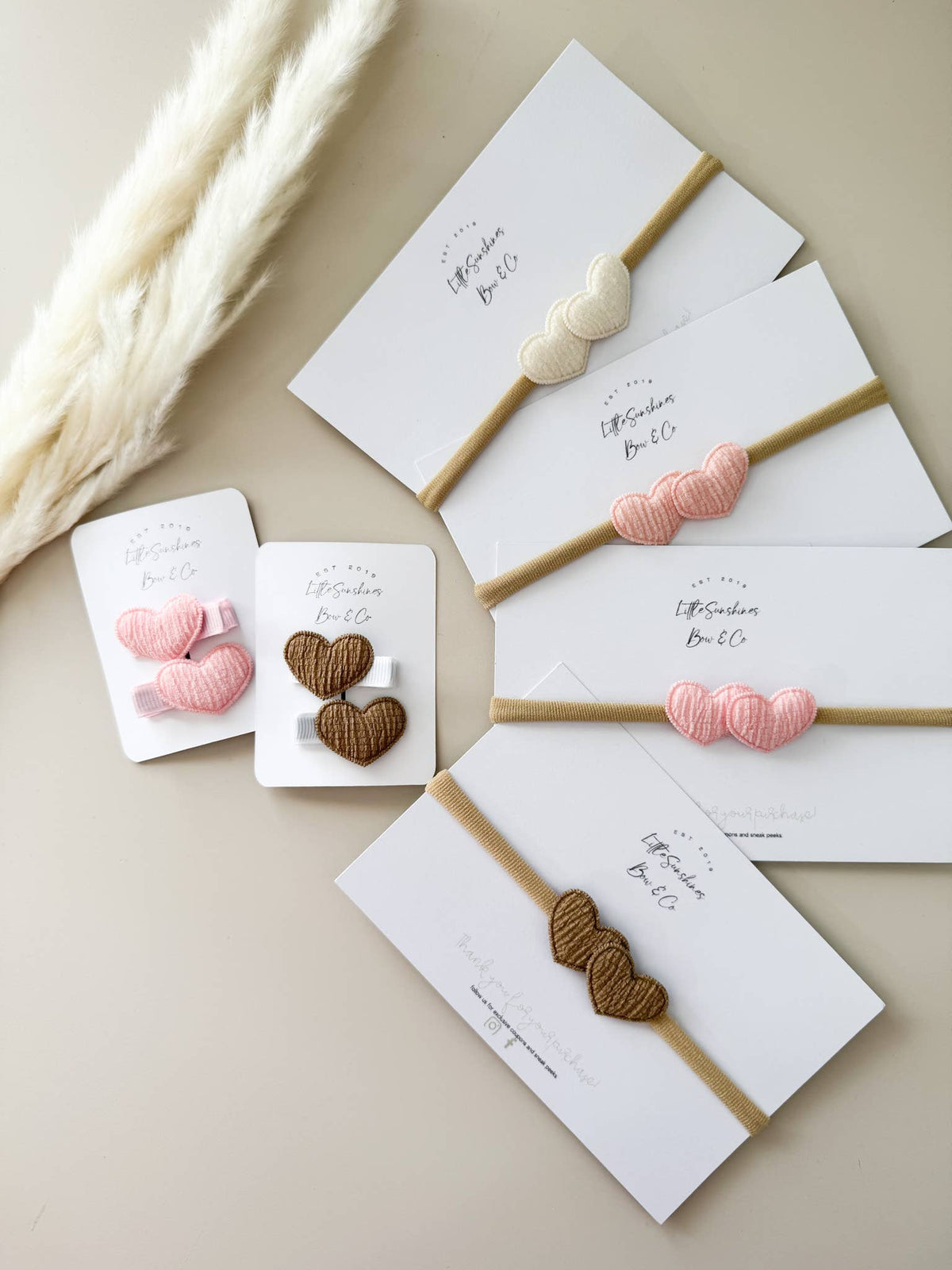 Double heart baby headbands in pink, cream, and brown on soft stretchy nylon bands for newborns and toddlers