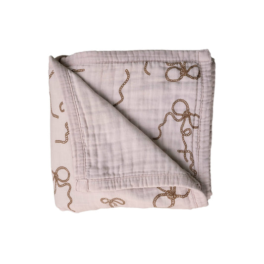 A folded beige muslin quilt with a lasso and rope pattern.