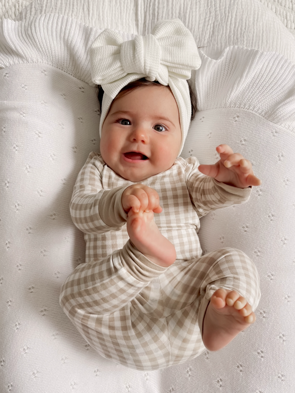 Neutral beige gingham two-piece baby lounge set displayed on a white textured blanket.