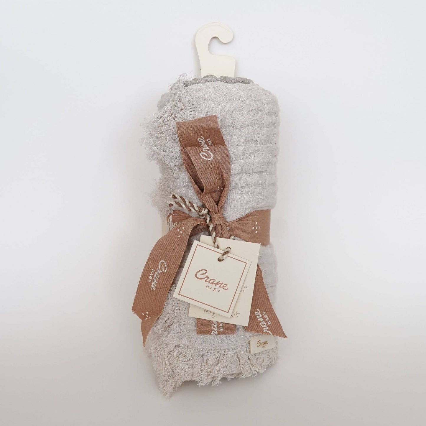 Flat lay of multi-layer muslin baby blanket in dove grey tones