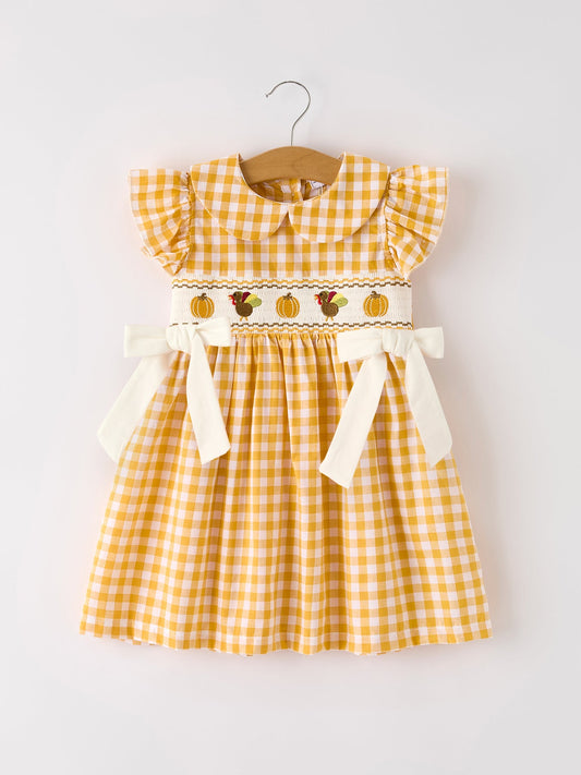 Girls yellow gingham Thanksgiving smocked dress with embroidered pumpkins, turkey, ruffle sleeves, and bow accents.