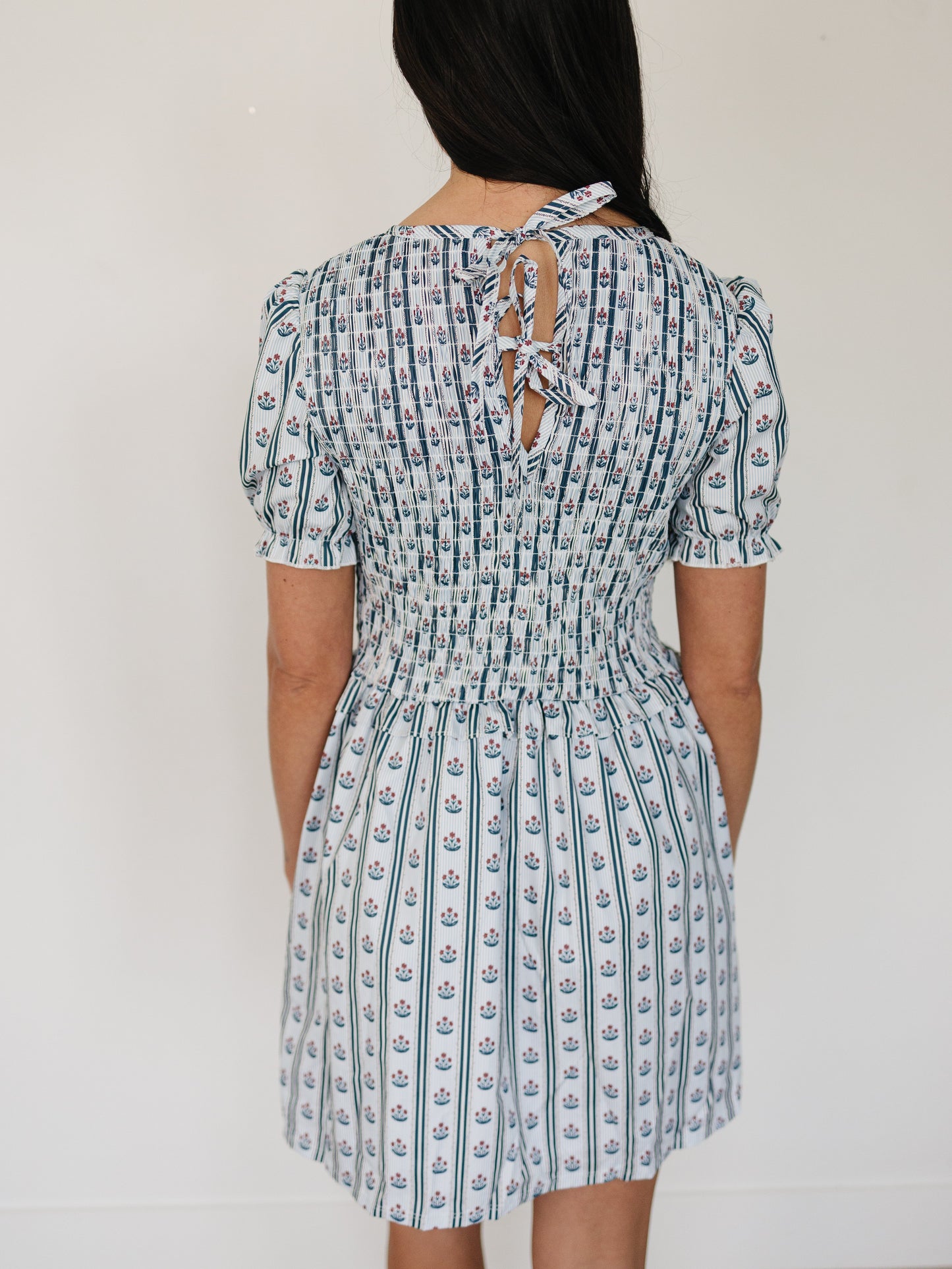 Woman wearing a patterned dress with a plain background